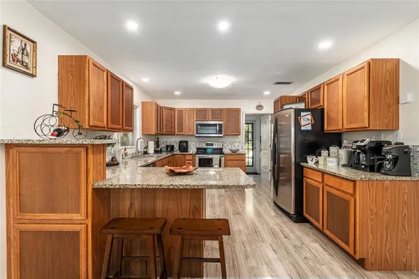 a kitchen with stainless steel appliances granite countertop a refrigerator a stove top oven a sink dishwasher and wooden cabinets with wooden floor