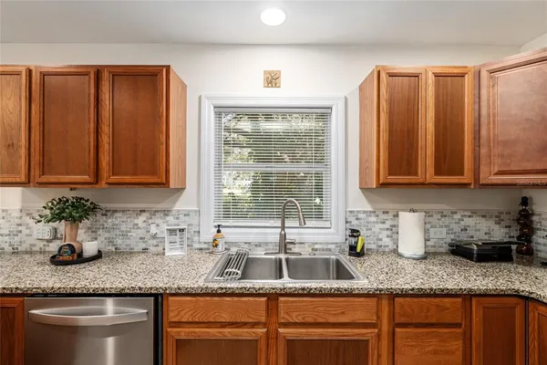 a kitchen with granite countertop stainless steel appliances a sink window and cabinets