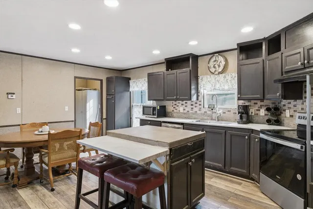 a kitchen with stainless steel appliances granite countertop a sink a stove a refrigerator cabinets and dining table