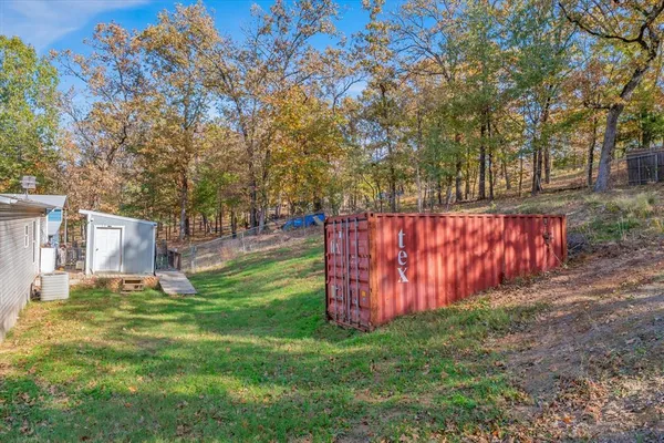 a view of a backyard with large trees and wooden fence