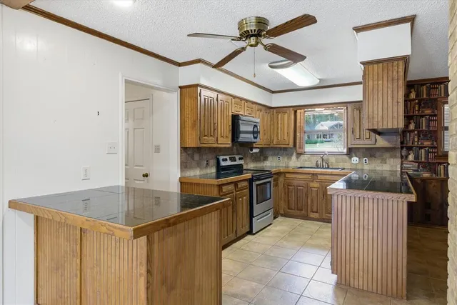 a kitchen with stainless steel appliances granite countertop a sink a stove top oven a counter space and cabinets