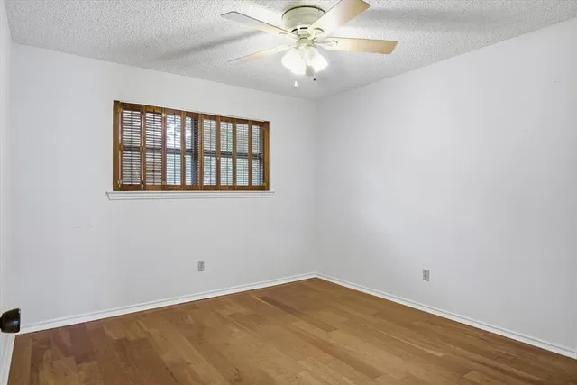 an empty room with a window and a fan