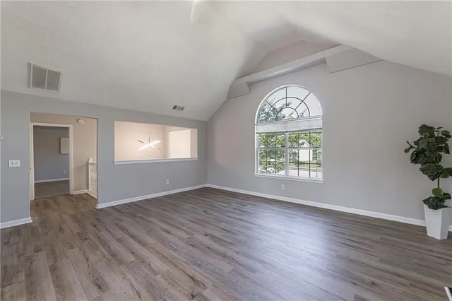 an empty room with wooden floor windows and entrance