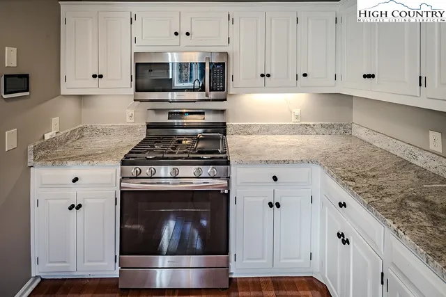 a kitchen with granite countertop white cabinets and stainless steel appliances