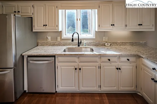 a kitchen with white cabinets and sink
