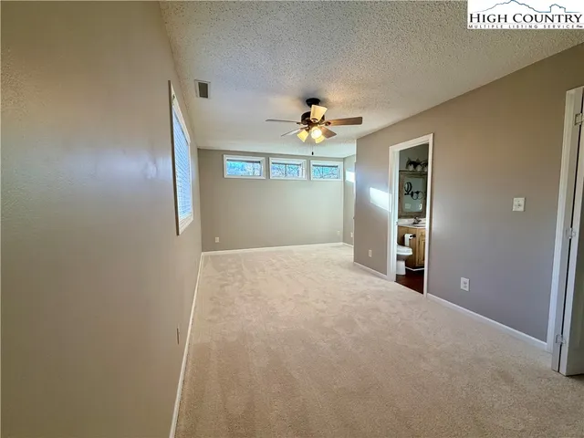 an empty room with windows and fan