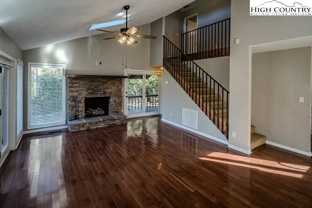an empty room with wooden floor fireplace and windows