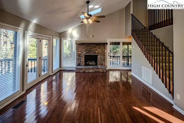 a view of an empty room with wooden floor fireplace and a window