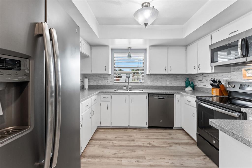 29 Pelican Lane Edgewater, FL 32141 - Photo 9 of 39 a kitchen with stainless steel appliances granite countertop a refrigerator a stove a sink and white cabinets with wooden floor