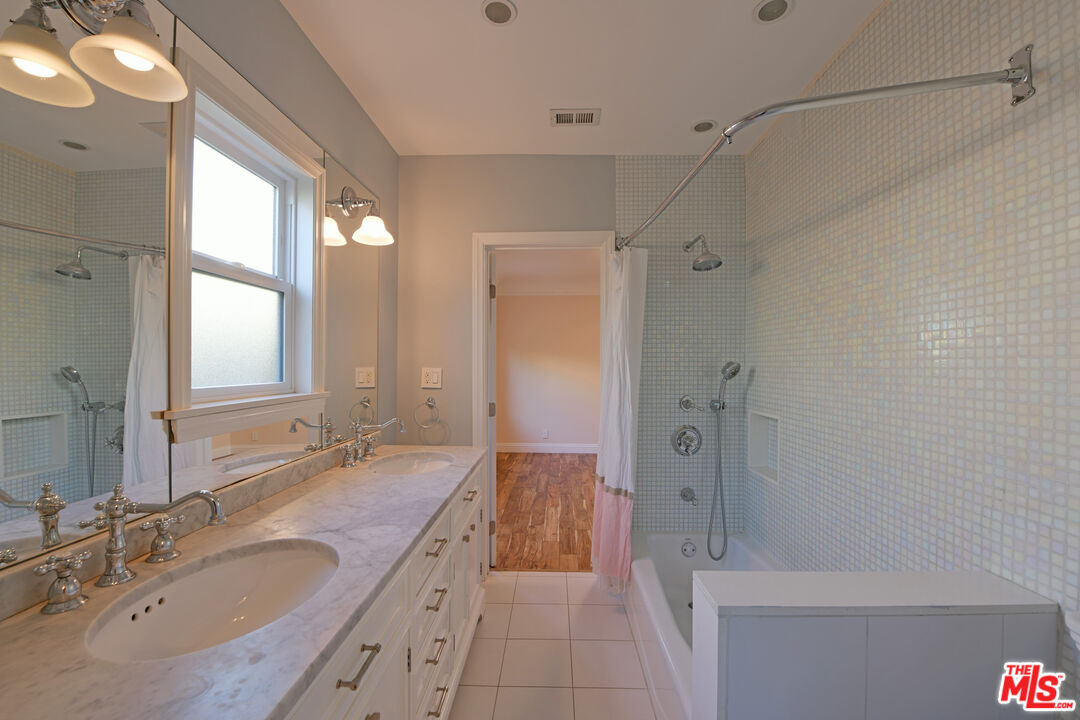 1657 South Point View Street Los Angeles, CA 90035 - Photo 21 of 50 a bathroom with a granite countertop sink a mirror a bathtub and shower