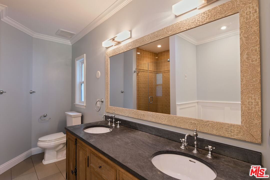 1657 South Point View Street Los Angeles, CA 90035 - Photo 28 of 50 a bathroom with a granite countertop sink a toilet a mirror and shower