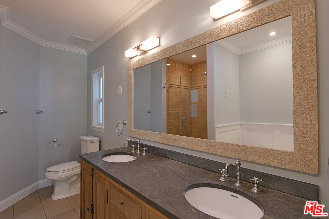 1657 South Point View Street Los Angeles, CA 90035 - Photo 29 of 50 a bathroom with a granite countertop sink a toilet a mirror and shower