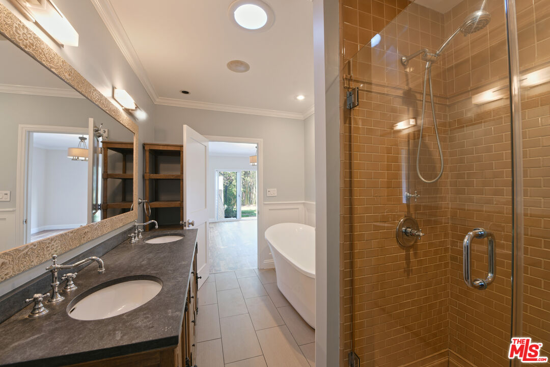 1657 South Point View Street Los Angeles, CA 90035 - Photo 30 of 50 a en suite bathroom with a granite countertop sink a mirror a glass door shower and bathtub