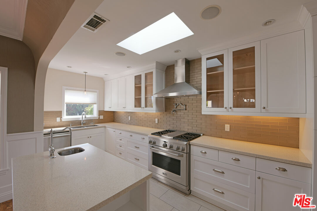 1657 South Point View Street Los Angeles, CA 90035 - Photo 9 of 50 a kitchen with stainless steel appliances a stove a sink and white cabinets