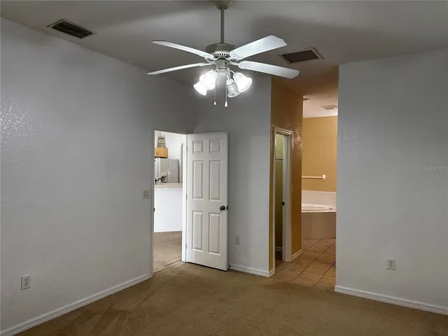 an empty room with closet and a chandelier fan