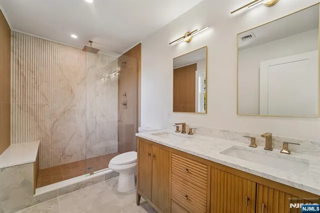 a bathroom with a double vanity sink toilet mirror and shower
