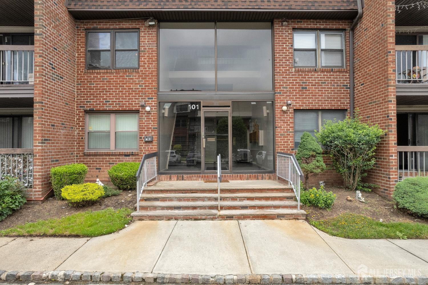 101 Beverly Hl Terrace, Unit M Woodbridge, NJ 07095 - Photo 2 of 28 a view of a brick house with potted plants and a bench