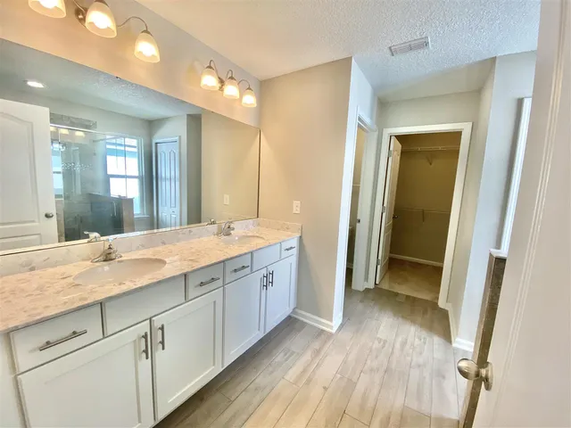 a spacious bathroom with a granite countertop sink mirror and a shower