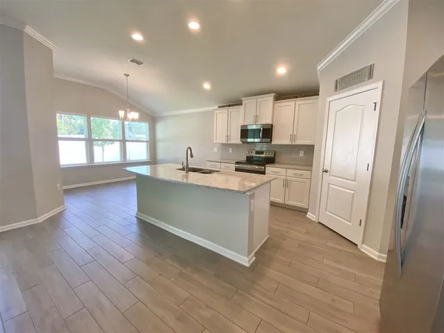 a kitchen with stainless steel appliances granite countertop a refrigerator a sink dishwasher a stove and a refrigerator with wooden floor