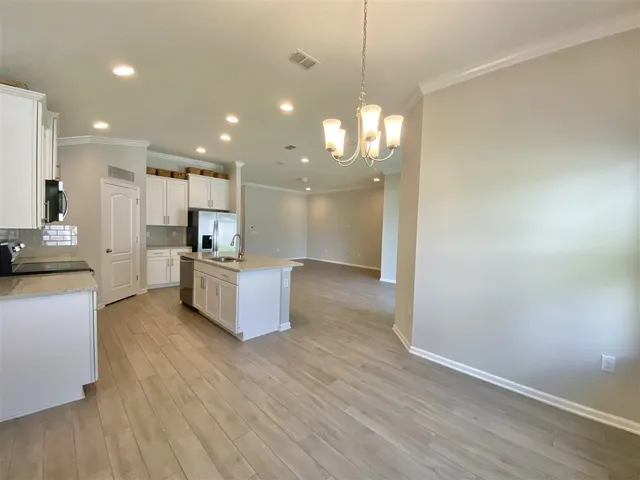 a large kitchen with granite countertop a large counter top a sink stainless steel appliances and cabinets