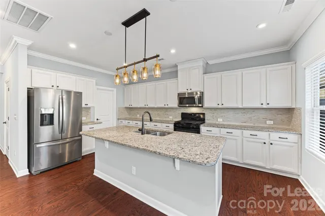 a kitchen with granite countertop white cabinets and stainless steel appliances