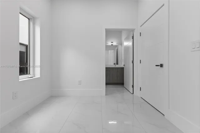 an empty room with windows and entrance to other room