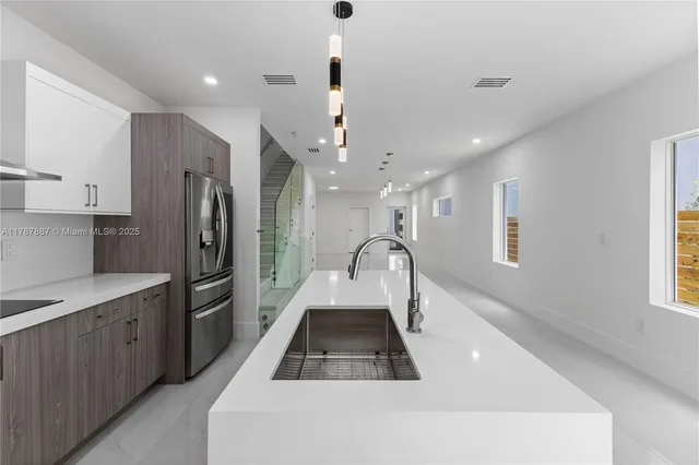 a kitchen with stainless steel appliances a refrigerator a sink dishwasher with a dining table and wooden floor