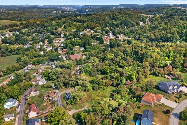 an aerial view of a houses with a lush green hillside