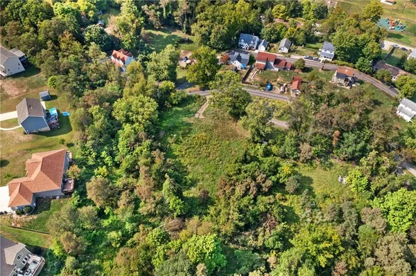 an aerial view of residential house with outdoor space and trees all around