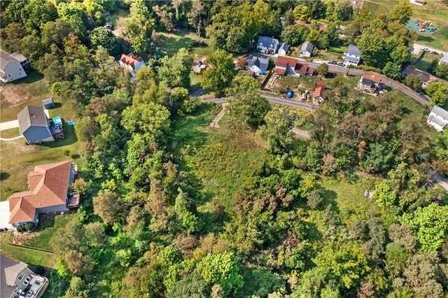 an aerial view of residential house with outdoor space and trees all around