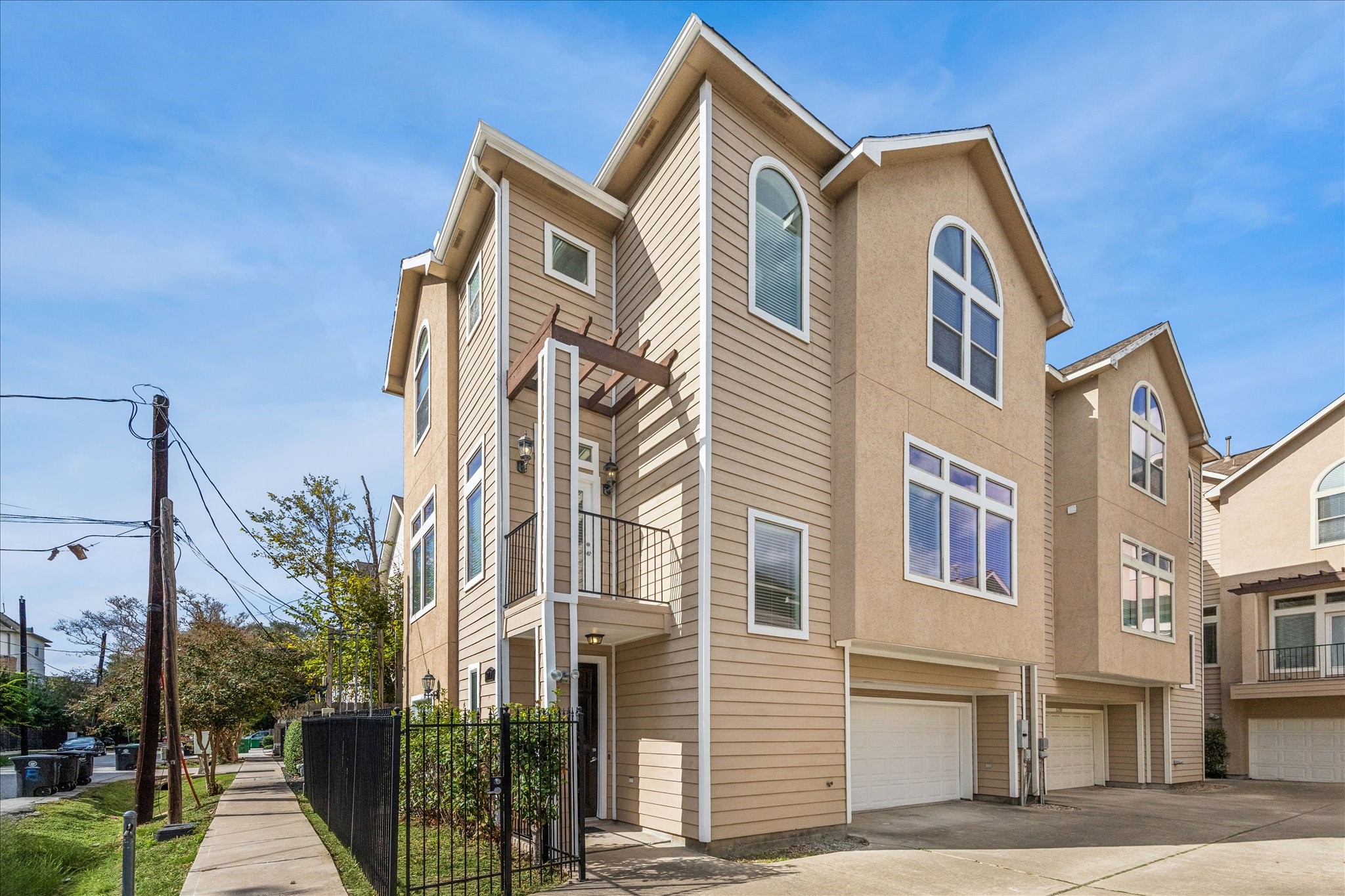 This corner-unit home features a clean, well-kept exterior with tall arched windows, a gated entry, and a private balcony. The two-car garage and wide driveway add convenience, while the sidewalk-lined street gives it an open, neighborhood feel.