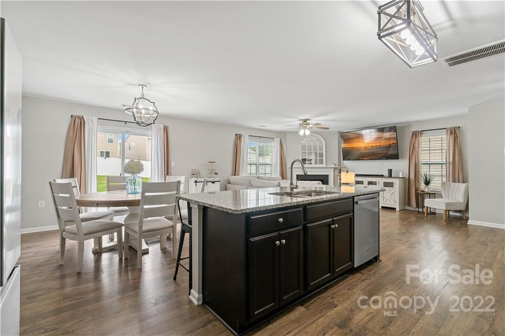 614 Shellbark Drive Concord, NC 28025 - Photo 12 of 30 a kitchen with stainless steel appliances granite countertop a stove top oven a dining table and chairs with wooden floor