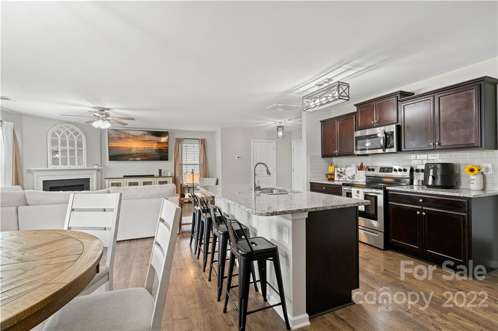 614 Shellbark Drive Concord, NC 28025 - Photo 10 of 30 a kitchen with stainless steel appliances granite countertop a stove top oven a sink dishwasher a dining table and chairs with wooden floor