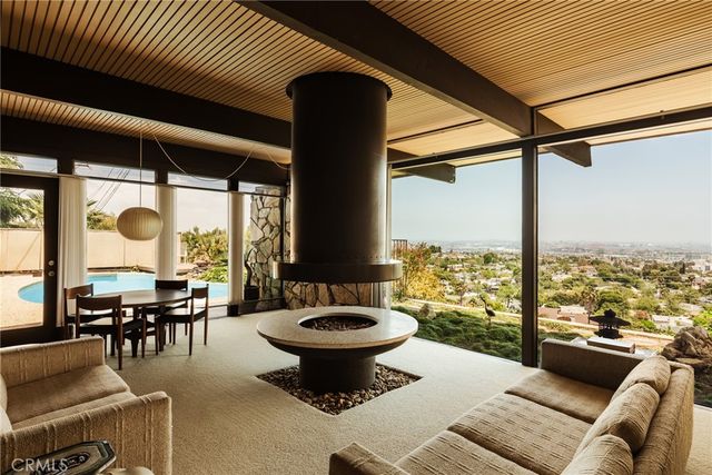 a living room with couches a table and chairs with a floor to ceiling window
