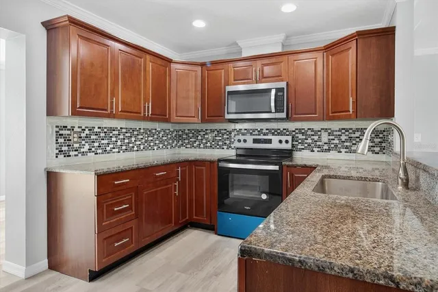a kitchen with stainless steel appliances granite countertop a stove microwave and sink