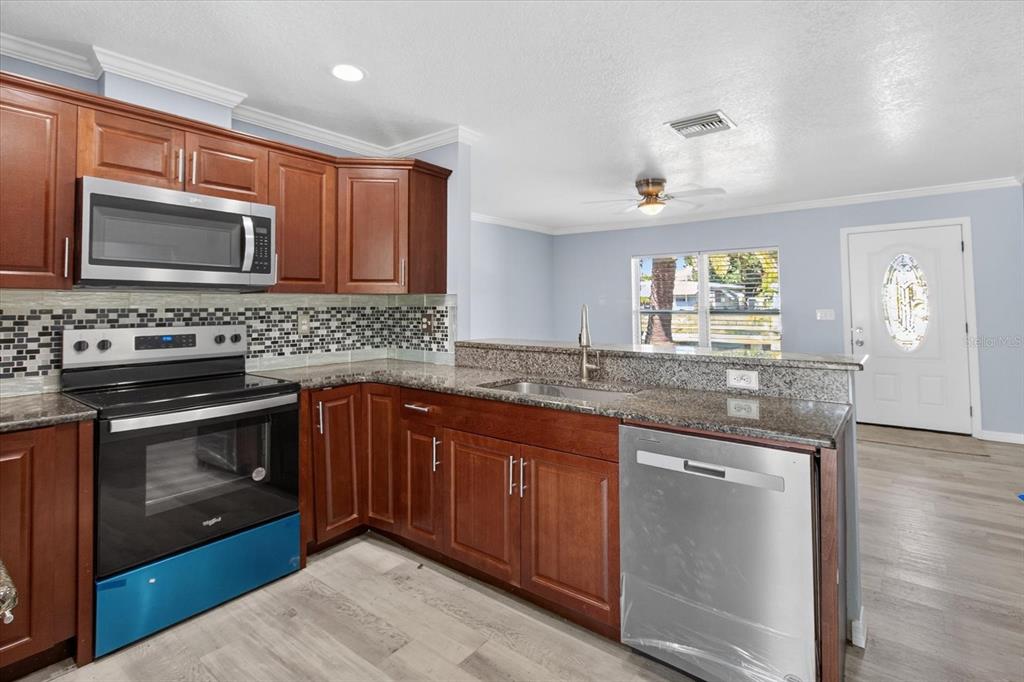 5352 Tangerine Drive New Port Richey, FL 34652 - Photo 20 of 76 a kitchen with stainless steel appliances granite countertop a stove microwave and sink