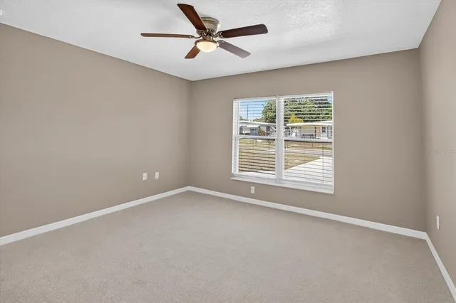 an empty room with a window and a ceiling fan