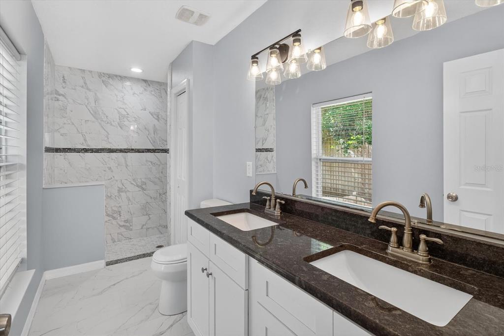 5352 Tangerine Drive New Port Richey, FL 34652 - Photo 27 of 76 a bathroom with a granite countertop sink a toilet a large mirror and shower