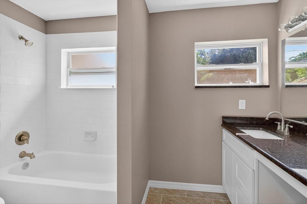 5352 Tangerine Drive New Port Richey, FL 34652 - Photo 39 of 76 a bathroom with a granite countertop sink a mirror and a bathtub