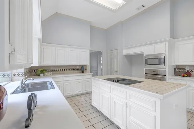 a kitchen with granite countertop a sink and white cabinets