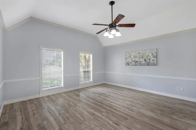 a view of an empty room with a window and wooden floor
