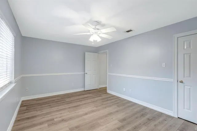 an empty room with a window and a ceiling fan