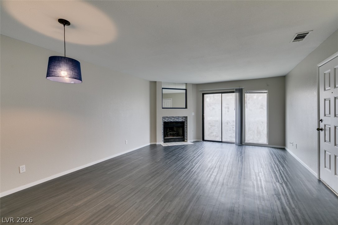 810 North Sloan Lane, Unit 103 Las Vegas, NV 89110 - Photo 2 of 16 Unfurnished living room with dark wood-style flooring, a fireplace with flush hearth, and baseboards