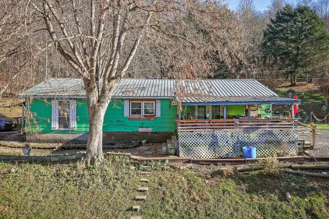 a front view of a house with a garden and tree