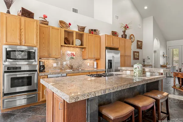 a large kitchen with granite countertop a large window and stainless steel appliances