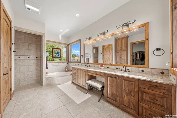 a bathroom with a double vanity sink a large mirror and a bathtub
