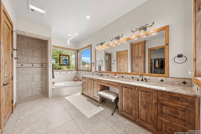 a bathroom with a double vanity sink a large mirror and a bathtub