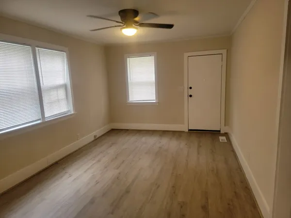 a view of an empty room with wooden floor and a window
