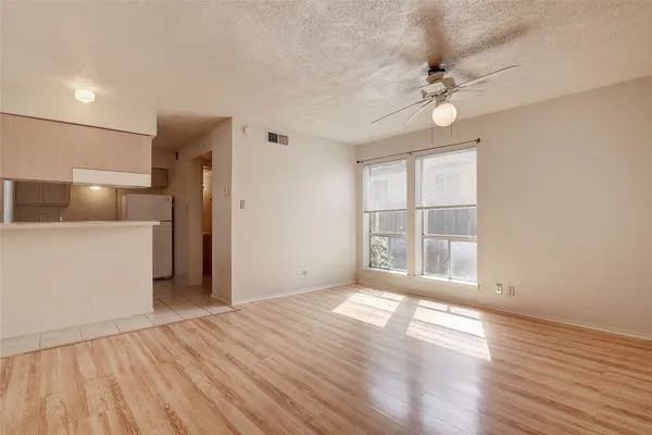 a view of a room with wooden floor and a kitchen space