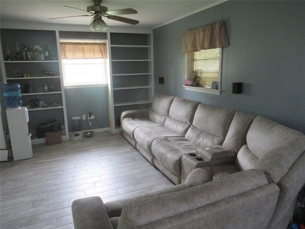 24133 Highway 157 Springhill, LA 71075 - Photo 12 of 19 Living area featuring light-toned wood-finish flooring, built-in shelving, and a ceiling fan with integrated lighting